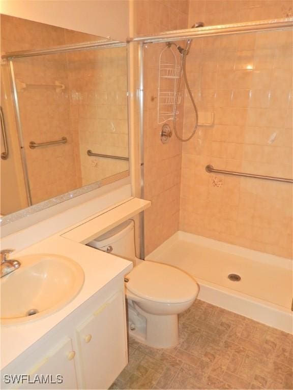 bathroom with toilet, a shower stall, and vanity