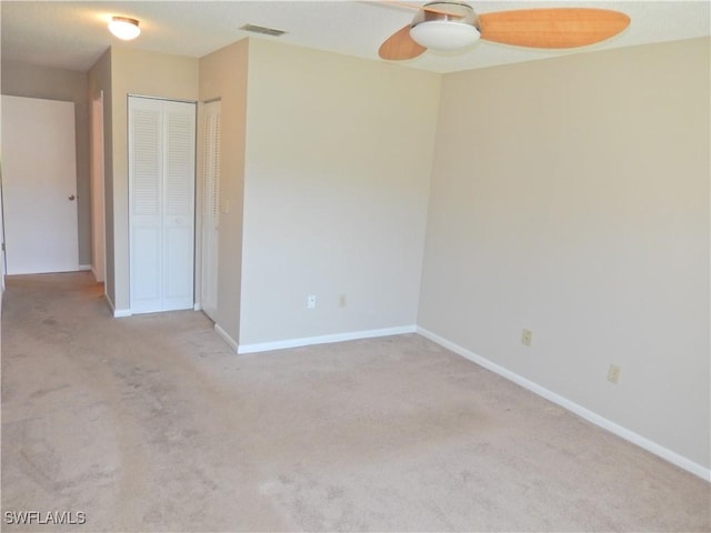 empty room with ceiling fan, carpet floors, visible vents, and baseboards