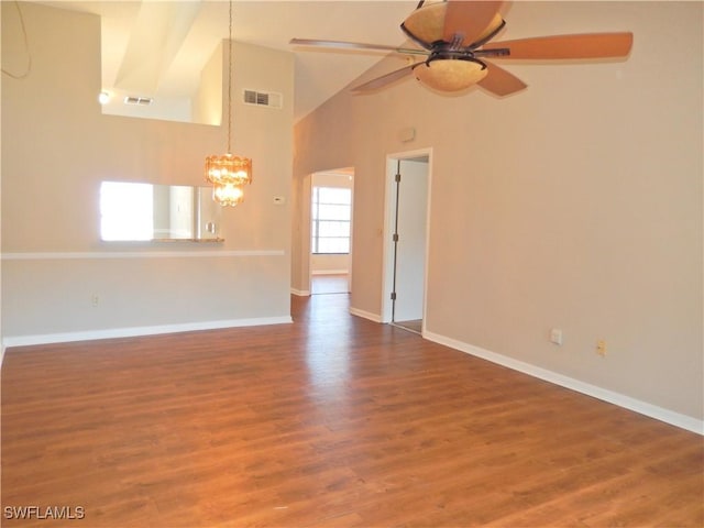 empty room featuring ceiling fan with notable chandelier, wood finished floors, visible vents, and baseboards