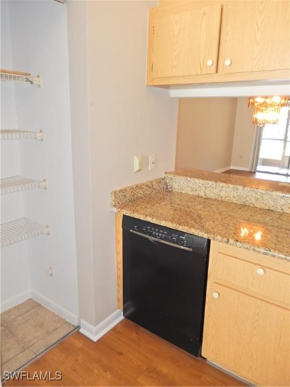 kitchen with light brown cabinetry, black dishwasher, and light wood-type flooring