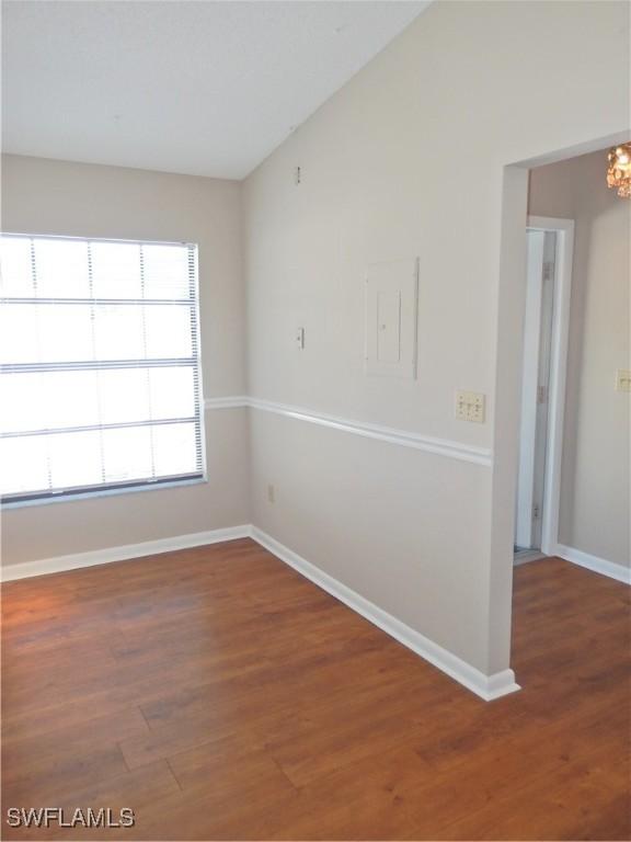 unfurnished room featuring vaulted ceiling, baseboards, and wood finished floors