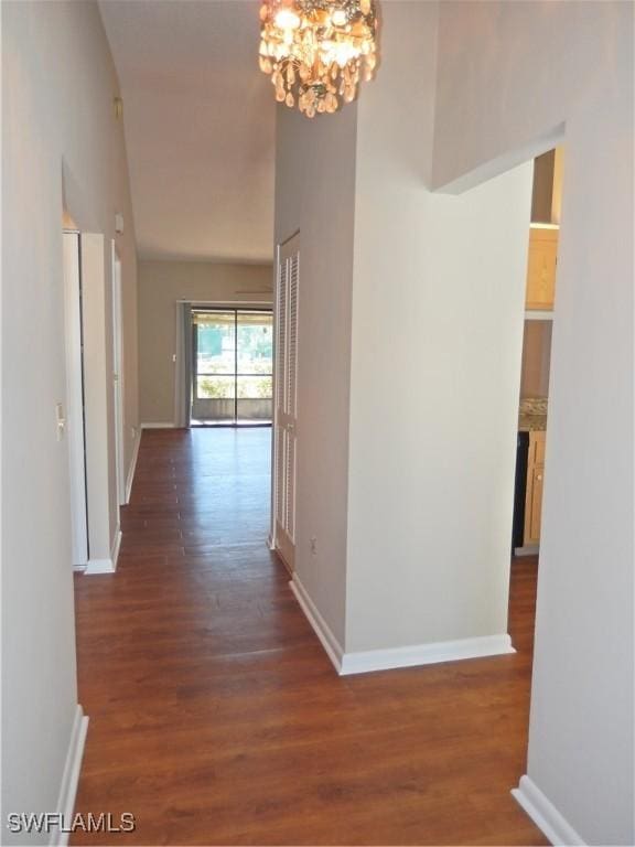 hallway with dark hardwood / wood-style flooring and a chandelier