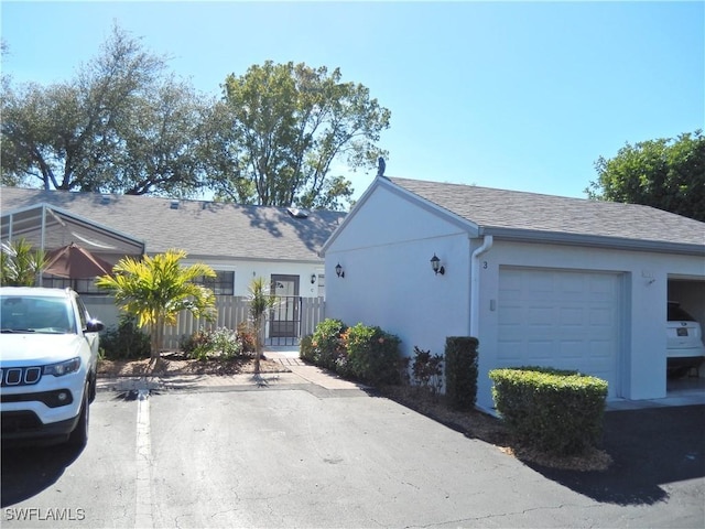 ranch-style house with a shingled roof, fence, and stucco siding