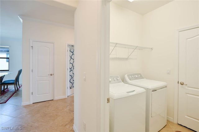 clothes washing area featuring light tile patterned flooring, ornamental molding, and washer and dryer