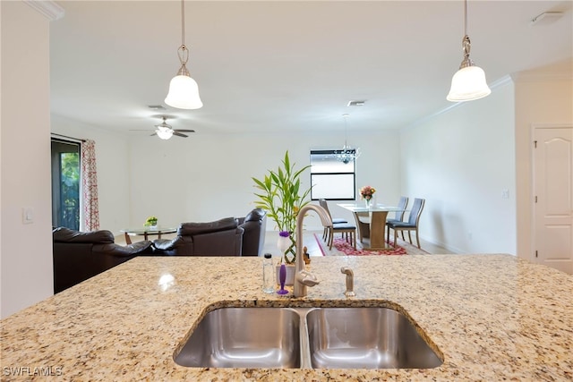 kitchen with pendant lighting, sink, and light stone countertops