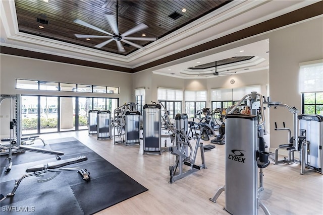 gym featuring wood ceiling, ceiling fan, ornamental molding, light hardwood / wood-style floors, and a raised ceiling