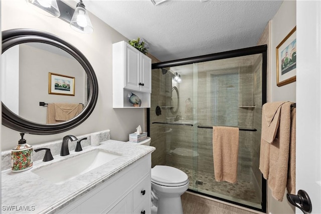 bathroom with toilet, a shower with shower door, and a textured ceiling