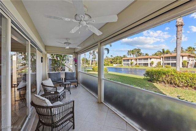 sunroom with ceiling fan and a water view