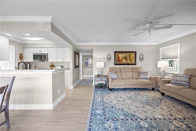 living room with ornamental molding, light wood-type flooring, and ceiling fan