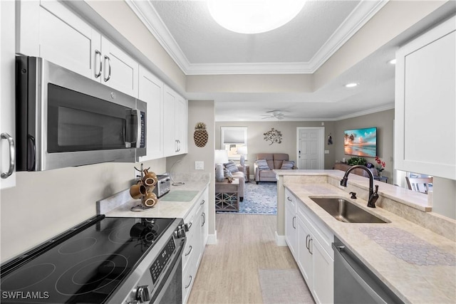 kitchen with sink, ornamental molding, stainless steel appliances, and white cabinets