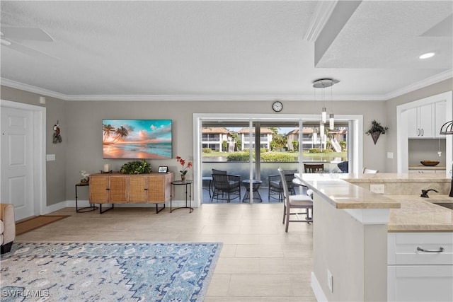 kitchen featuring white cabinetry, pendant lighting, ornamental molding, and light stone countertops