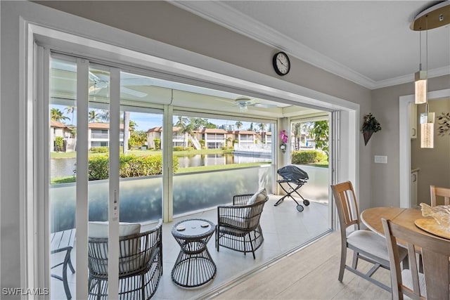 sunroom featuring ceiling fan, a healthy amount of sunlight, and a water view