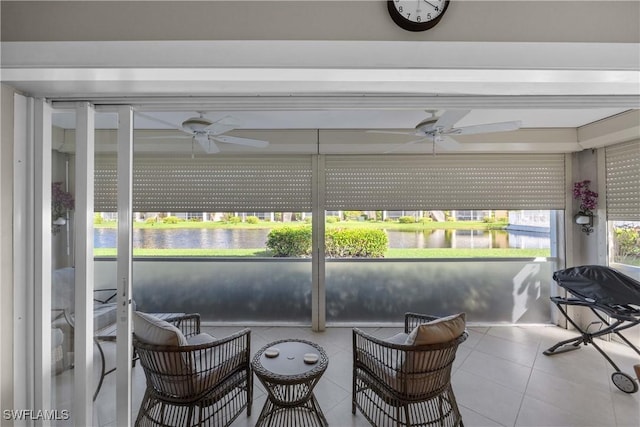 sunroom featuring ceiling fan and a water view