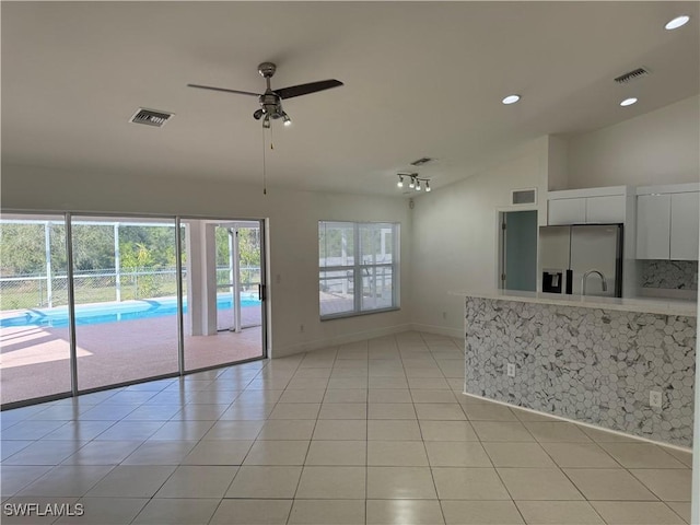 interior space featuring lofted ceiling, light tile patterned floors, visible vents, and stainless steel refrigerator with ice dispenser