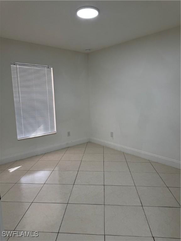 unfurnished room featuring light tile patterned floors and baseboards