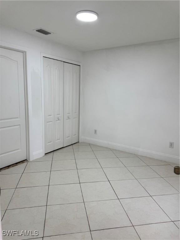 unfurnished bedroom with a closet, light tile patterned flooring, visible vents, and baseboards