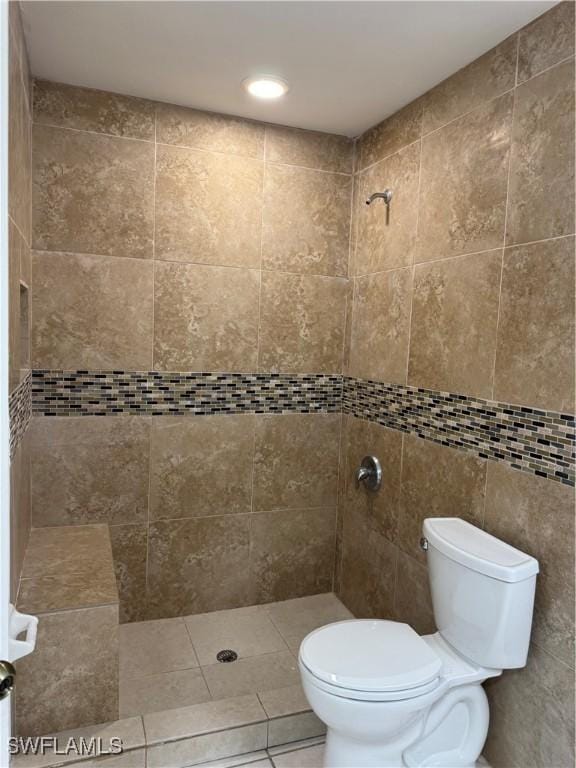 full bathroom with toilet, tile patterned flooring, tile walls, and tiled shower