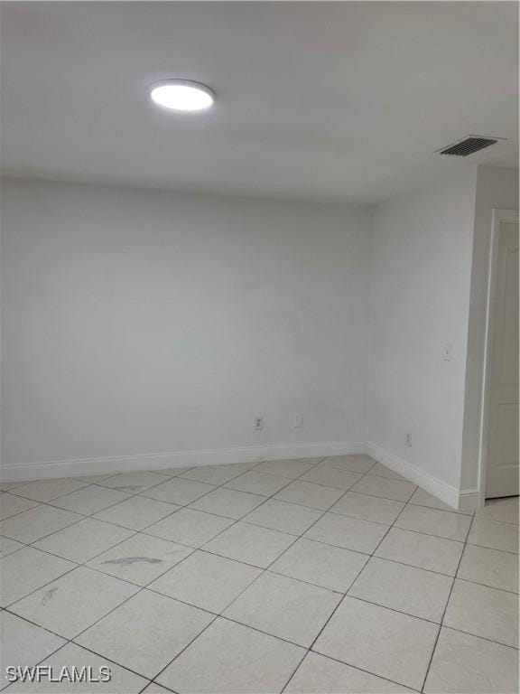 empty room with light tile patterned floors, visible vents, and baseboards