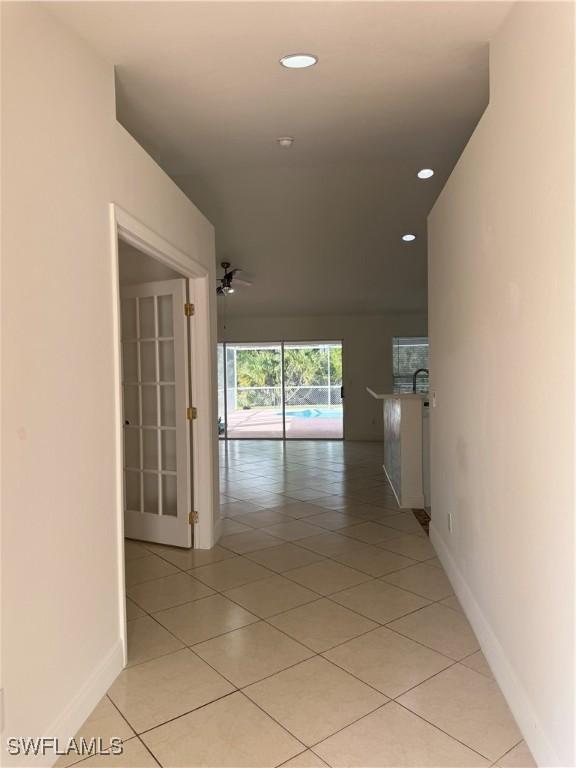 hallway with light tile patterned floors, baseboards, and recessed lighting