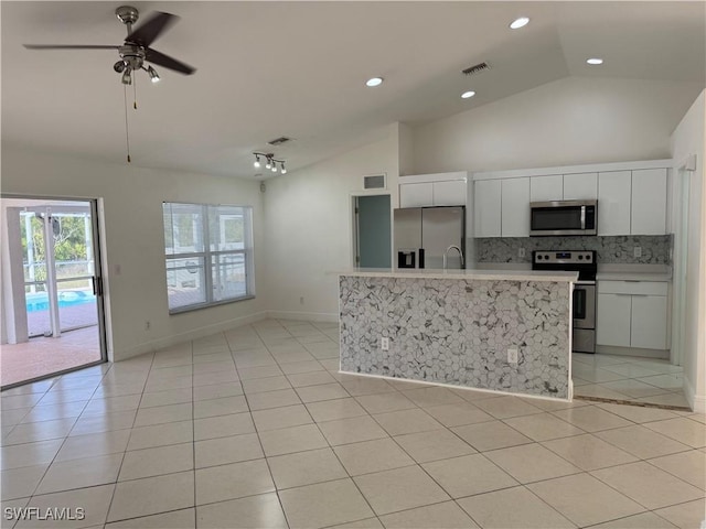 kitchen featuring stainless steel appliances, light countertops, decorative backsplash, light tile patterned flooring, and vaulted ceiling