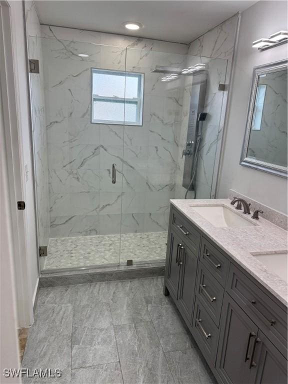 bathroom featuring a sink, a marble finish shower, and double vanity