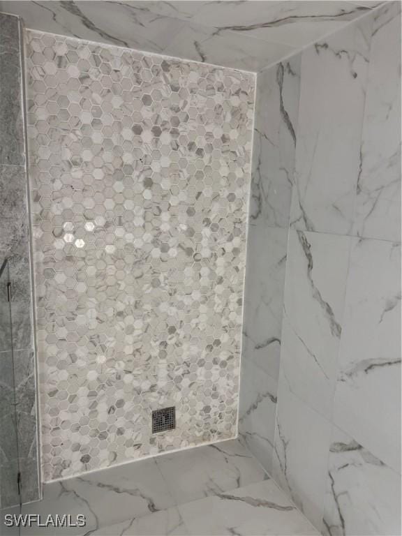 bathroom with marble finish floor and a shower