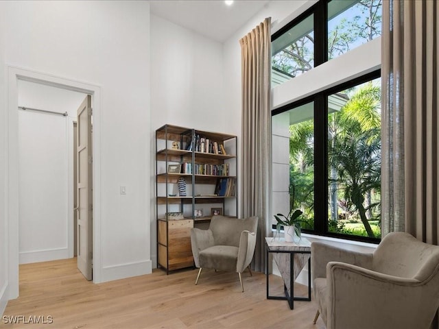 sitting room with a towering ceiling and light hardwood / wood-style floors