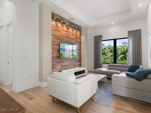 living room with light hardwood / wood-style flooring and a tray ceiling