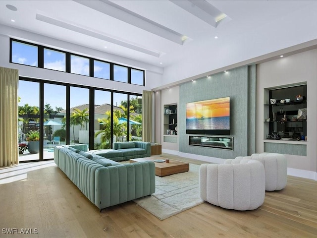 living room featuring wood-type flooring, built in features, and a high ceiling