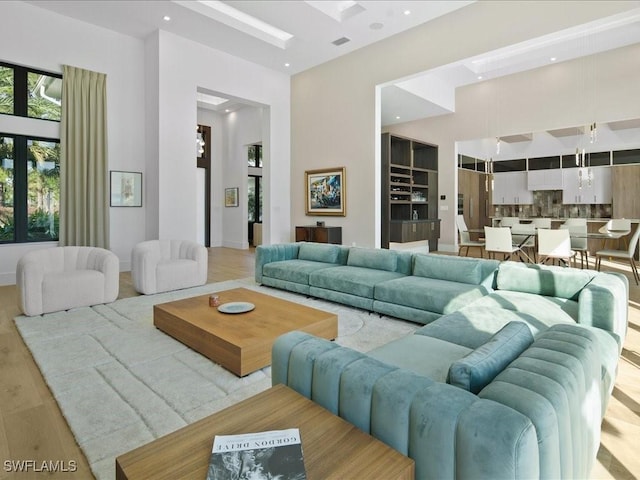 interior space featuring a towering ceiling, a skylight, and light hardwood / wood-style floors