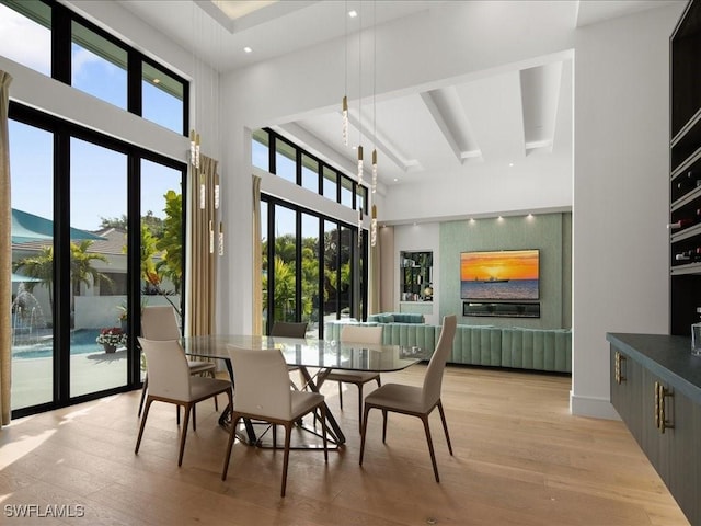 dining room with a high ceiling, light hardwood / wood-style flooring, and a wealth of natural light