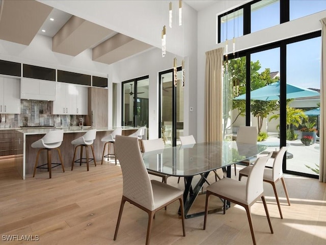 dining space featuring a high ceiling and light wood-type flooring