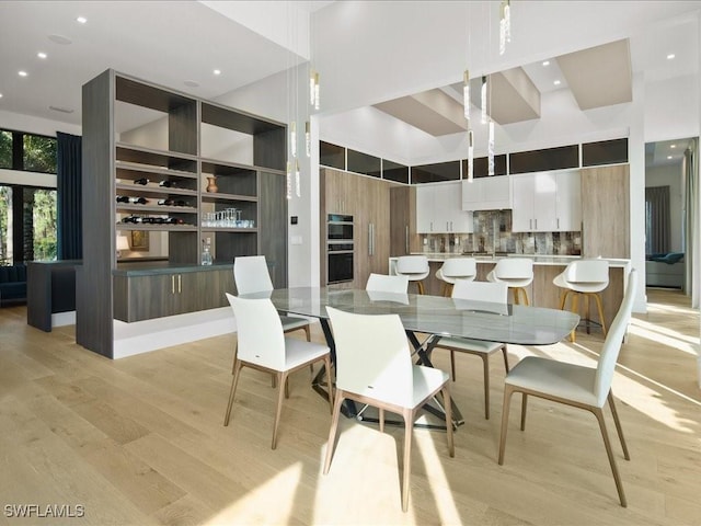 dining space featuring light hardwood / wood-style floors and a high ceiling