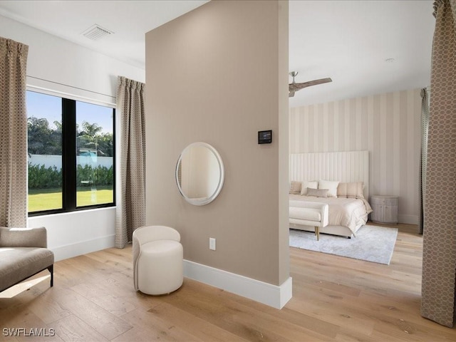 living area featuring light hardwood / wood-style flooring, ceiling fan, and a water view