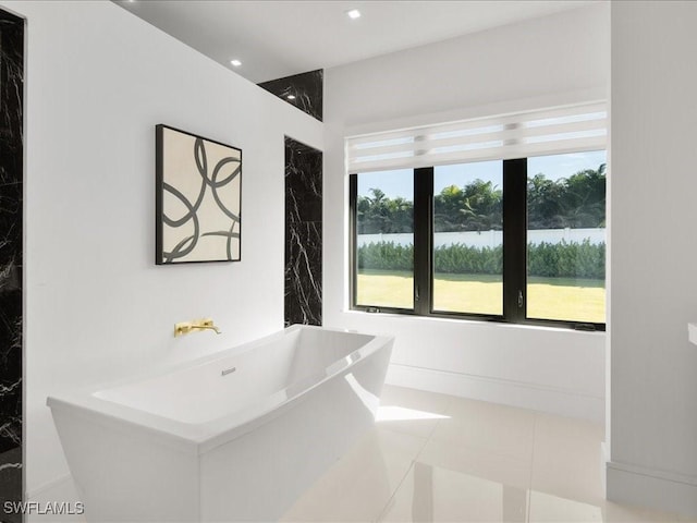 bathroom with tile patterned floors, a bathing tub, and a water view