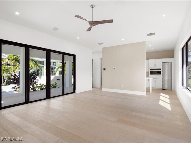 unfurnished living room with ceiling fan, a healthy amount of sunlight, and light wood-type flooring