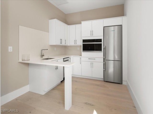 kitchen featuring sink, kitchen peninsula, white cabinets, and appliances with stainless steel finishes