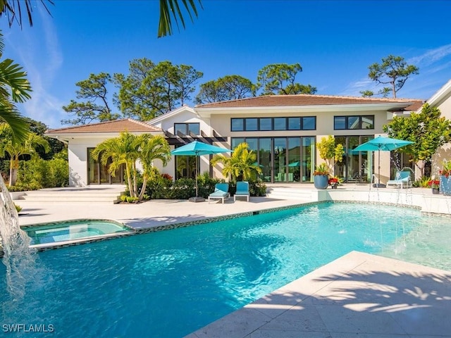 view of pool with a patio area, pool water feature, and an in ground hot tub