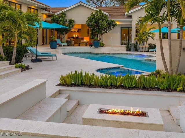 view of pool with an in ground hot tub, pool water feature, a patio area, and an outdoor fire pit