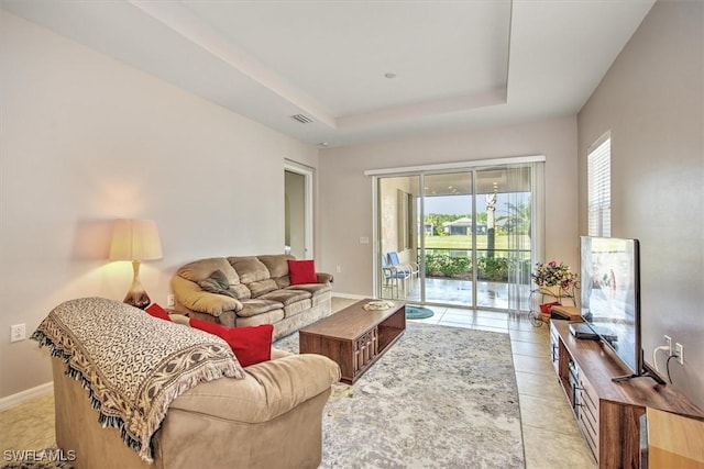 living room with a raised ceiling and light tile patterned floors