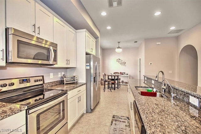 kitchen featuring white cabinets, stainless steel appliances, sink, and dark stone countertops