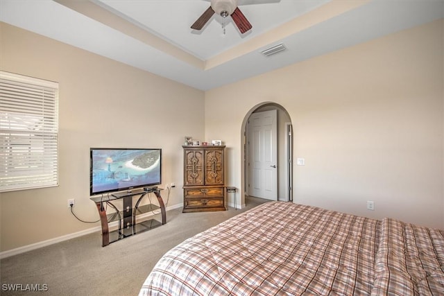 bedroom with ceiling fan, a tray ceiling, and carpet