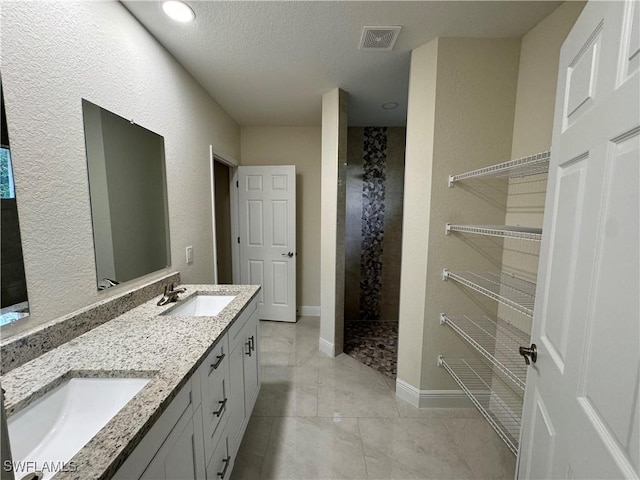 bathroom featuring walk in shower, vanity, and a textured ceiling