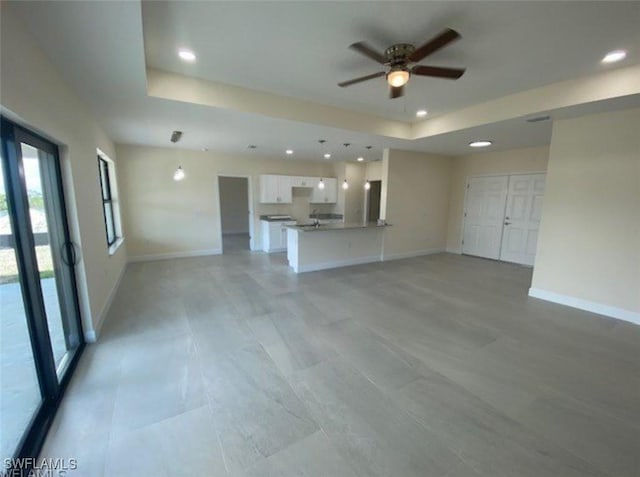 unfurnished living room with a raised ceiling and ceiling fan