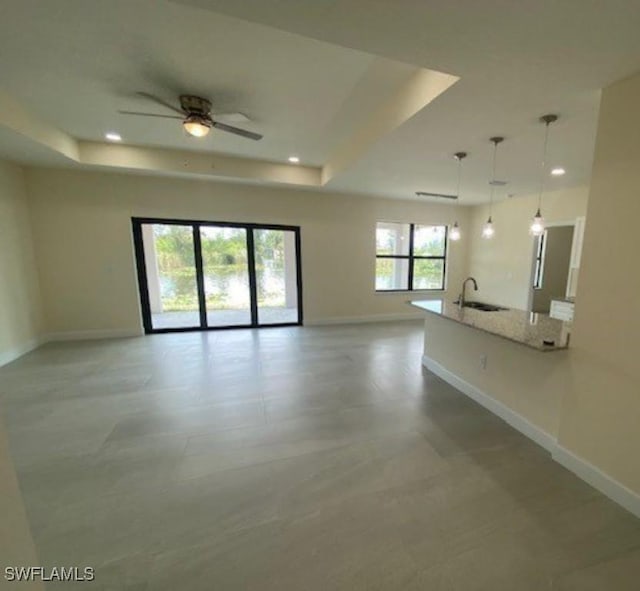 unfurnished room featuring sink, a tray ceiling, and ceiling fan