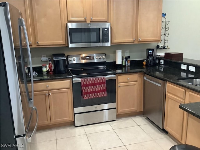 kitchen featuring dark stone countertops, stainless steel appliances, and light tile patterned flooring