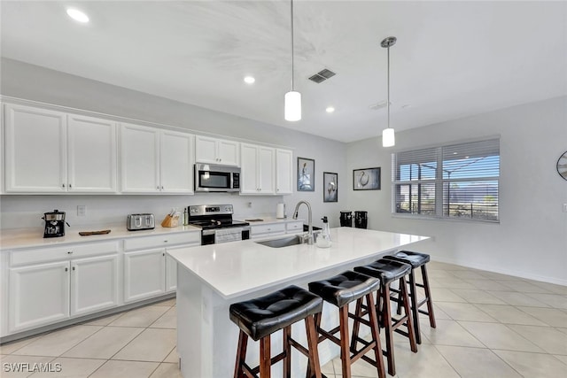 kitchen featuring sink, decorative light fixtures, appliances with stainless steel finishes, a kitchen island with sink, and white cabinets