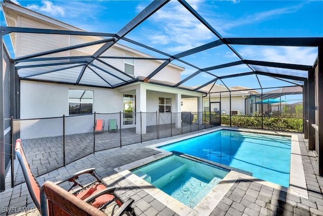 view of pool with an in ground hot tub, glass enclosure, and a patio