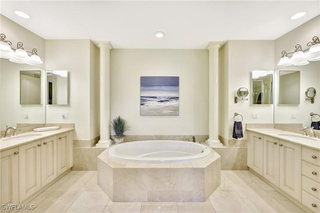 bathroom featuring vanity, tiled tub, and decorative columns