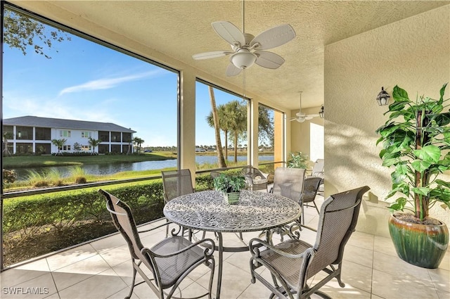 sunroom / solarium featuring a water view and ceiling fan